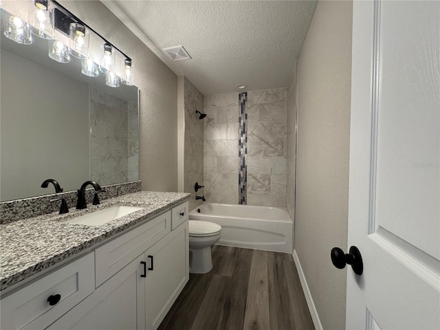 bathroom featuring visible vents, a textured wall, toilet, a textured ceiling, and wood finished floors