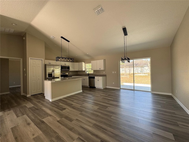 kitchen with stainless steel appliances, a sink, white cabinetry, vaulted ceiling, and dark wood-style floors