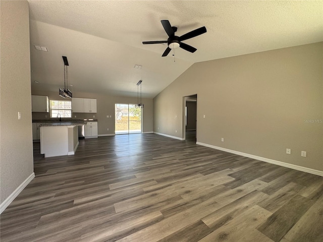 unfurnished living room featuring dark wood-style floors, baseboards, vaulted ceiling, and a ceiling fan