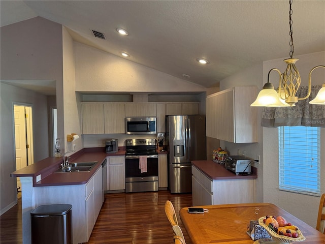 kitchen featuring visible vents, a peninsula, vaulted ceiling, stainless steel appliances, and a sink