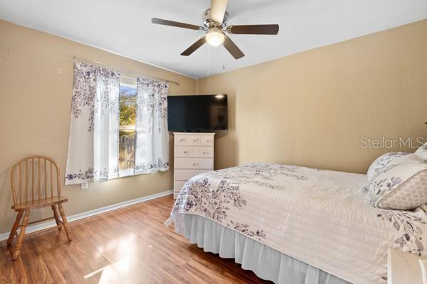 bedroom featuring wood finished floors, a ceiling fan, and baseboards