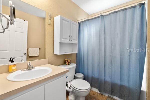 bathroom with toilet, shower / tub combo with curtain, and vanity