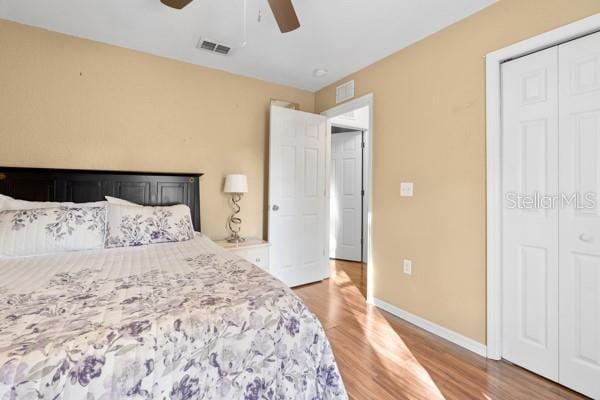 bedroom with baseboards, visible vents, a closet, and wood finished floors