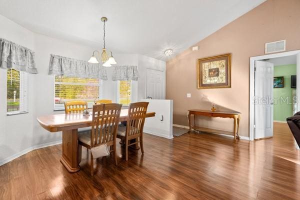 dining room featuring lofted ceiling, visible vents, wood finished floors, a chandelier, and baseboards