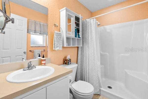 bathroom featuring vanity, a shower stall, and toilet