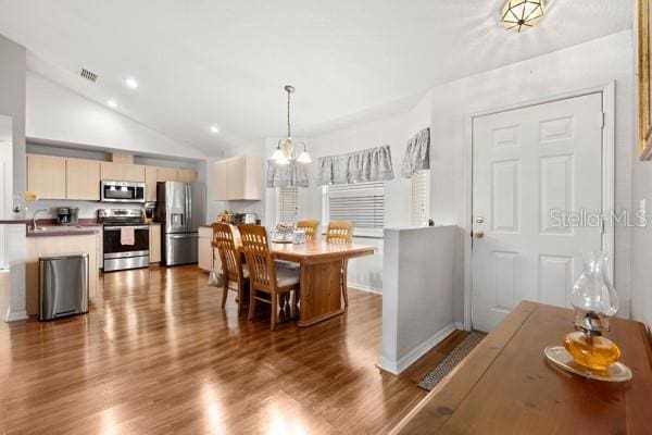 dining area featuring lofted ceiling, recessed lighting, wood finished floors, visible vents, and an inviting chandelier