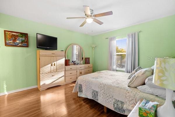 bedroom with ceiling fan, baseboards, and wood finished floors