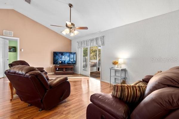 living room with vaulted ceiling, wood finished floors, and visible vents