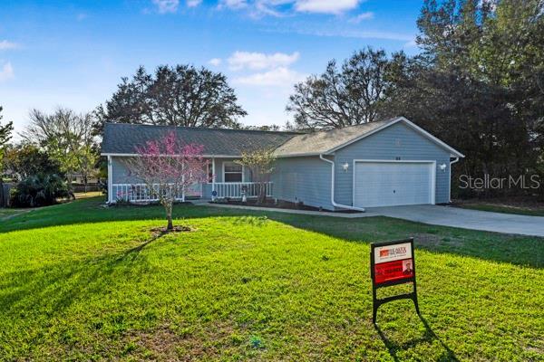 ranch-style house with a garage, concrete driveway, a front lawn, and covered porch