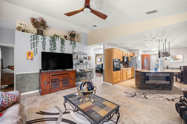 living area with visible vents, vaulted ceiling, baseboards, and ceiling fan