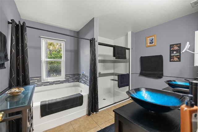 full bath with a textured ceiling, a garden tub, vanity, tile patterned floors, and a stall shower