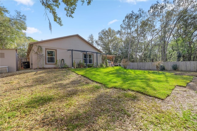 rear view of house featuring fence, a lawn, and stucco siding