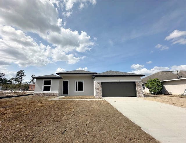 prairie-style house with stucco siding, a garage, concrete driveway, and stone siding