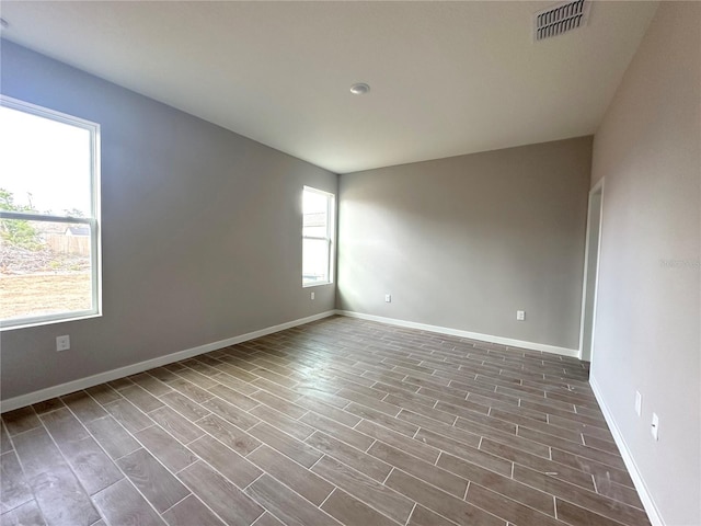 unfurnished room featuring baseboards, visible vents, and wood finished floors