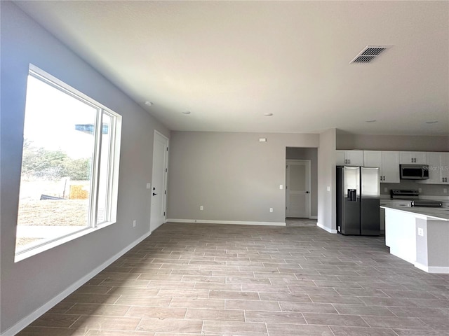 unfurnished living room featuring baseboards, light wood-style flooring, and visible vents