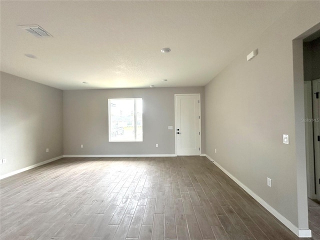 spare room with baseboards, visible vents, and wood finished floors