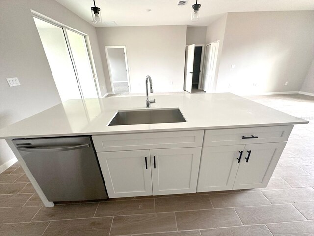 kitchen with white cabinets, light countertops, a sink, open floor plan, and stainless steel dishwasher