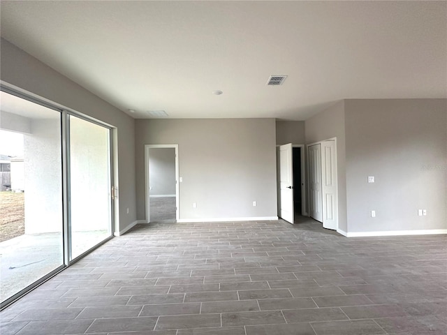 unfurnished bedroom featuring two closets, wood finished floors, baseboards, and visible vents