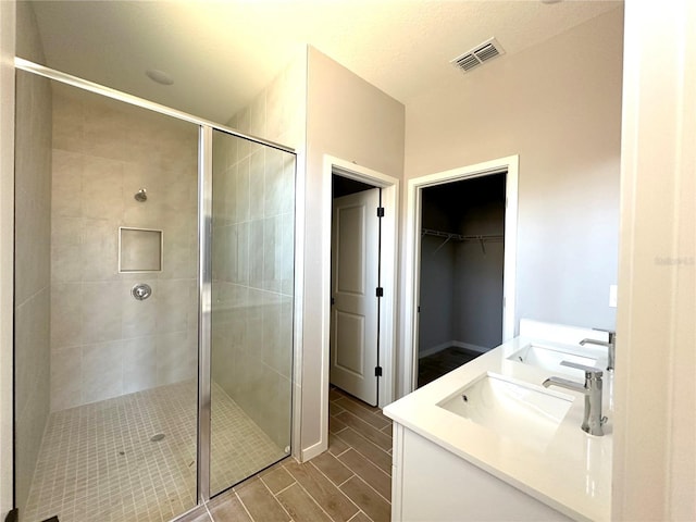 bathroom with a shower stall, wood tiled floor, visible vents, and a sink