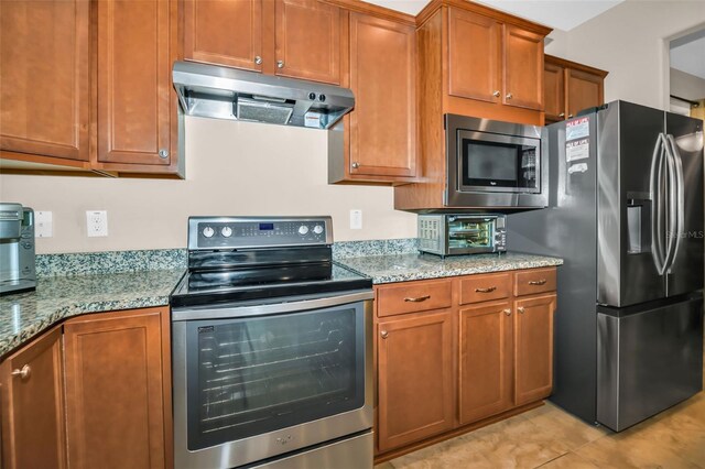 7234 SW 91st Ct, Ocala, FL 34481 - kitchen with stainless steel appliances, under cabinet range hood, brown cabinetry, and light stone countertops