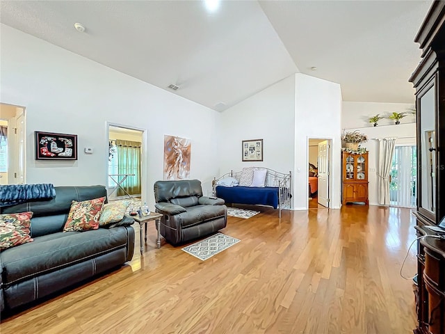 living area with light wood finished floors, visible vents, and high vaulted ceiling