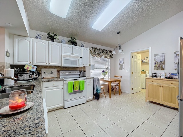 kitchen featuring white appliances, vaulted ceiling, white cabinets, and a sink