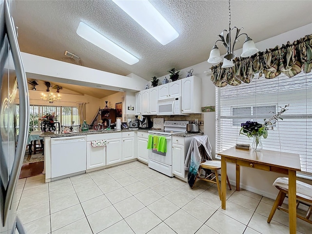 kitchen featuring light tile patterned floors, a notable chandelier, white appliances, white cabinets, and vaulted ceiling