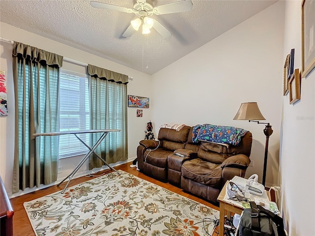 living room with lofted ceiling, ceiling fan, a textured ceiling, and wood finished floors