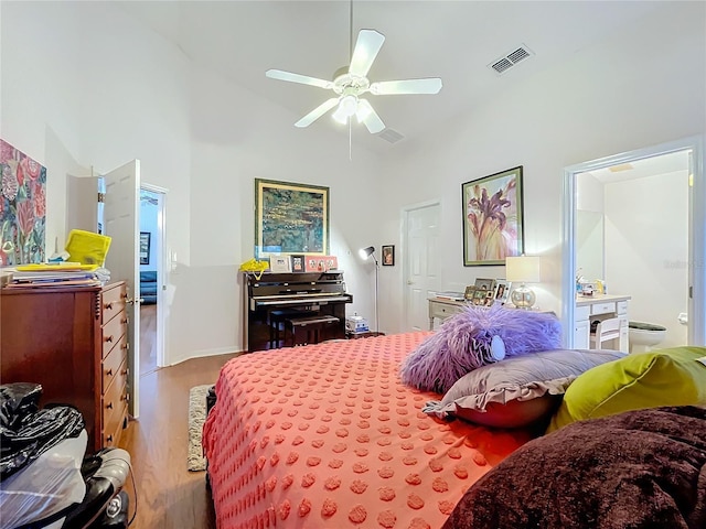 bedroom with a towering ceiling, wood finished floors, and visible vents