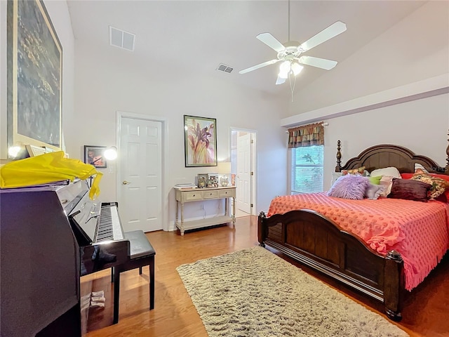 bedroom with high vaulted ceiling, a ceiling fan, visible vents, and wood finished floors