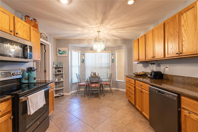 kitchen featuring dark countertops, light tile patterned floors, stainless steel appliances, a notable chandelier, and a textured ceiling