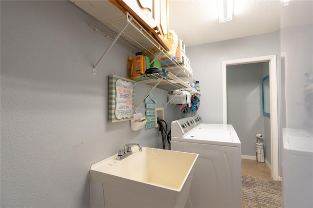 laundry room featuring baseboards, laundry area, light tile patterned flooring, a sink, and washing machine and dryer