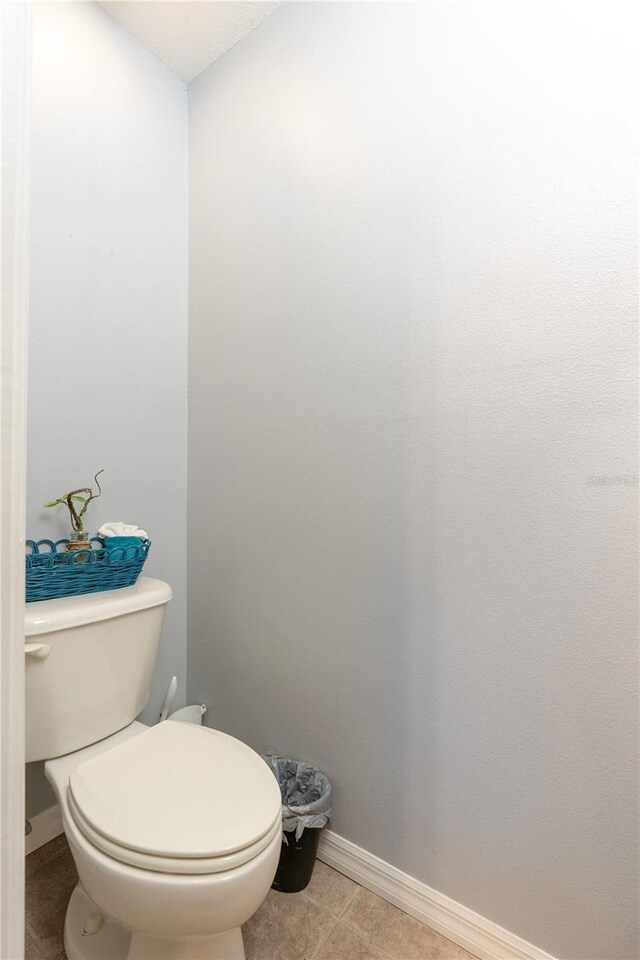 bathroom with baseboards, toilet, and tile patterned flooring