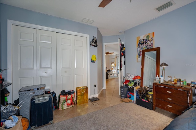 tiled bedroom featuring a ceiling fan, visible vents, and a closet