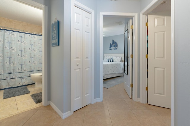 corridor featuring baseboards and light tile patterned flooring