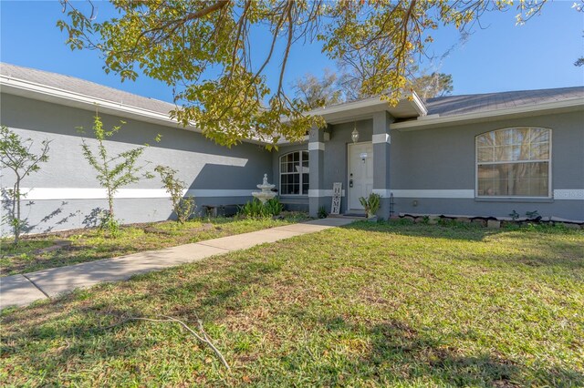 ranch-style house featuring stucco siding and a front lawn