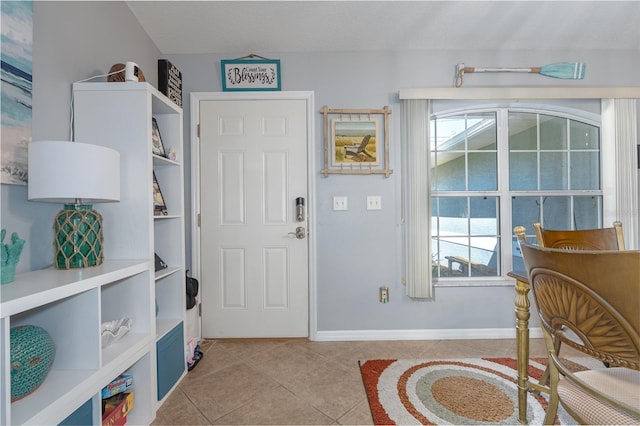 foyer featuring light tile patterned flooring, a healthy amount of sunlight, and baseboards