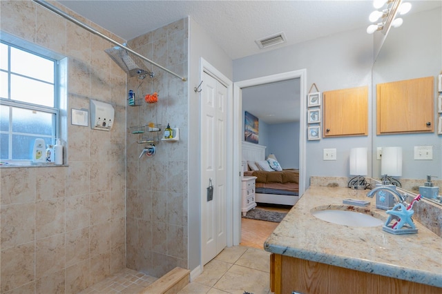 full bathroom featuring visible vents, vanity, ensuite bathroom, and a tile shower