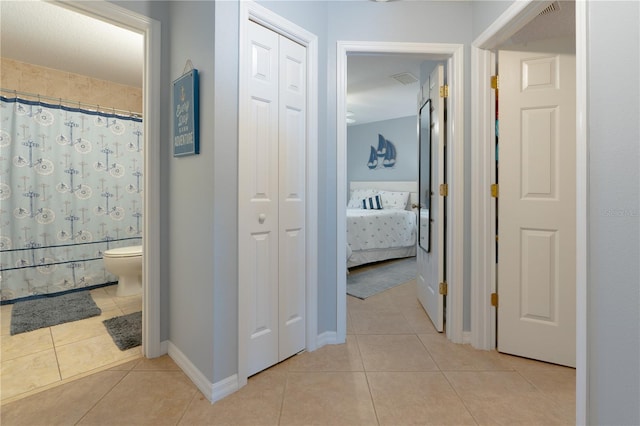 corridor with light tile patterned flooring and baseboards