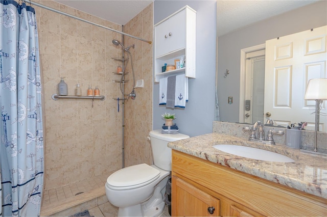 bathroom with a tile shower, toilet, and vanity