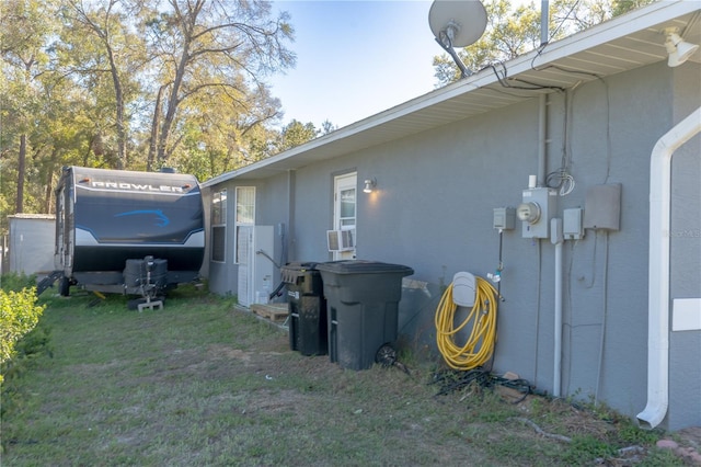 view of side of home with stucco siding, a lawn, and cooling unit