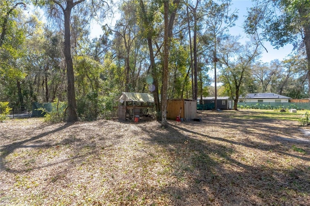 view of yard featuring an outdoor structure, fence, and a shed