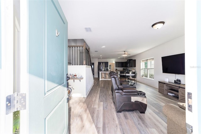 living room with stairs, light wood-type flooring, and visible vents