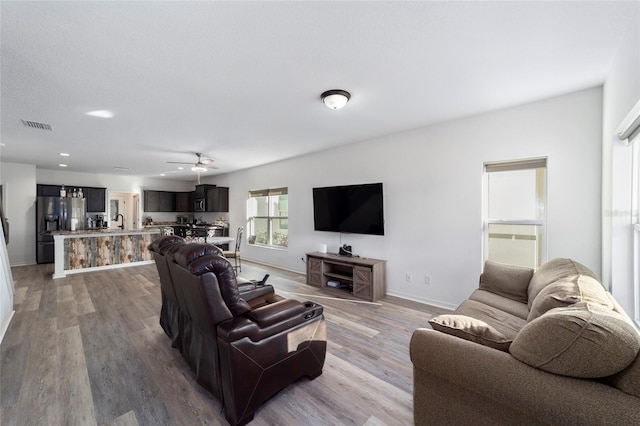 living room with recessed lighting, visible vents, light wood-style flooring, and baseboards