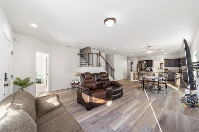 living room with light wood-type flooring, stairway, baseboards, and recessed lighting