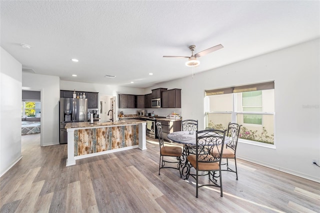 interior space featuring light wood-style flooring, baseboards, a textured ceiling, and recessed lighting