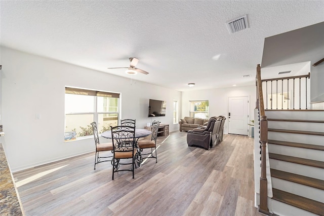 dining room with visible vents, ceiling fan, stairs, a textured ceiling, and light wood-type flooring