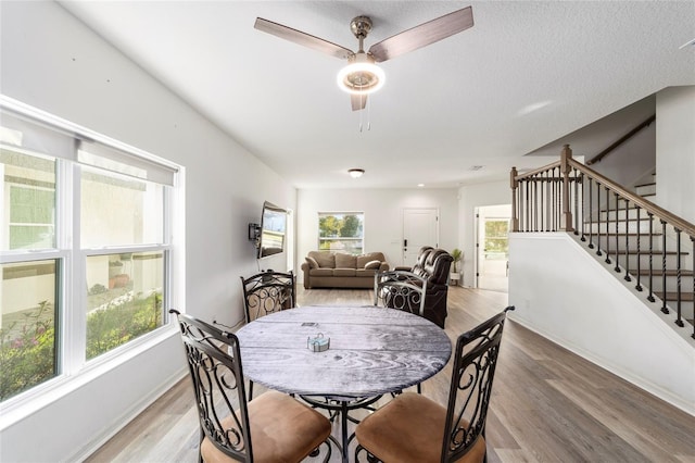 dining space with a healthy amount of sunlight, stairway, baseboards, and wood finished floors