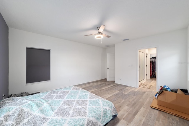 bedroom with light wood-type flooring, a spacious closet, visible vents, and a ceiling fan