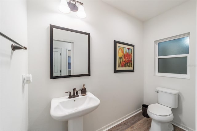 bathroom featuring wood finished floors, a sink, toilet, and baseboards